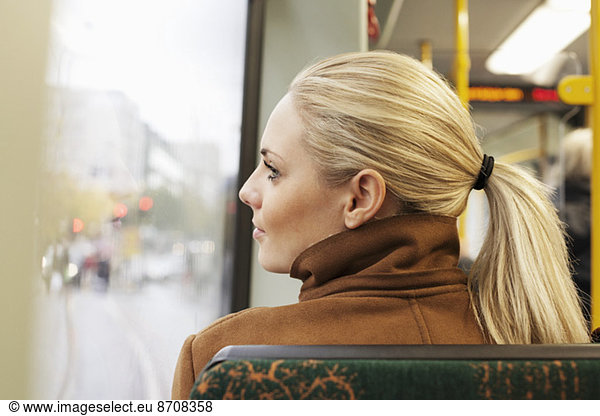 Rear view of woman looking out through bus window