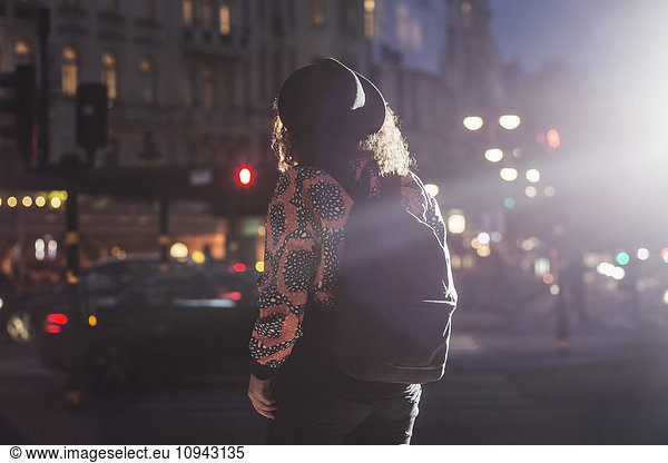 Rear view of woman on city street at night
