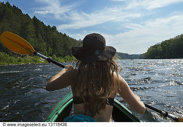 Rear view of woman rowing boat in river