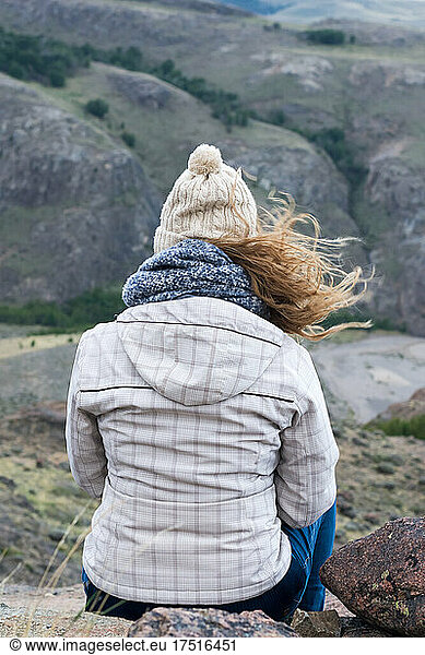 Rear view of woman sitting at the mountain