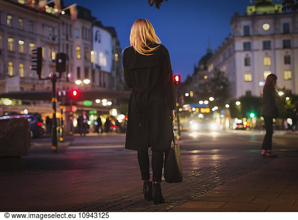 Rear view of woman walking on city street at night