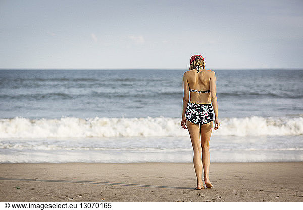 Rear view of woman walking on shore at beach, Rear view of woman walking on shore at beach