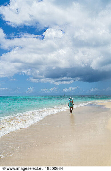 Rear view of woman walking seaside on white sand beach  Caribbean