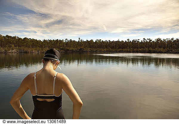 Rear view of woman wearing swimwear standing against lake