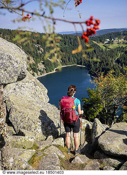 Rear view of women hiker looking at view of forest from Hans rock edge above Lac Blanc at Rocher Hans  France