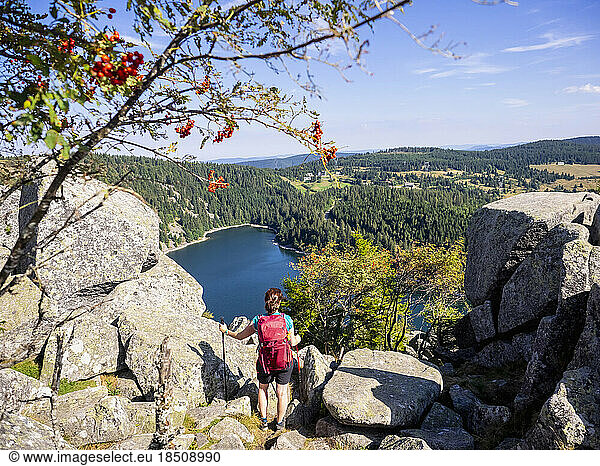 Rear view of women hiker looking at view of forest from Hans rock edge above Lac Blanc at Rocher Hans  France