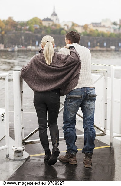 Rear view of young couple leaning on railing outdoors