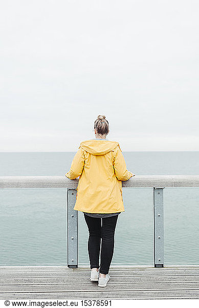Rear view of young woman wearing yellow rain coat, Rear view of young woman wearing yellow rain coat