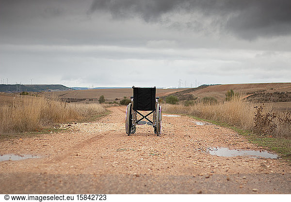 Rear vision of a wheelchair isolated in the middle of a path