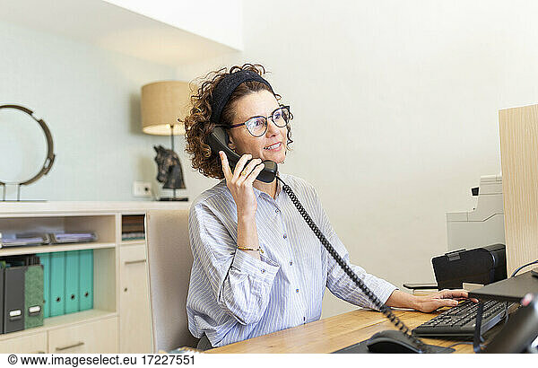 Receptionist talking on telephone at desk in hotel