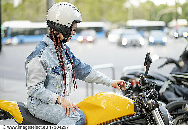 Rechte Seitenaufnahme einer jungen Frau auf einem gelben Motorrad