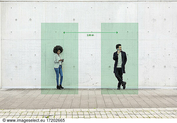 Rechtecke zur Visualisierung sozialer Distanzierung  die einen Mann und eine Frau abdecken  die mit Smartphones in der Hand im Freien stehen
