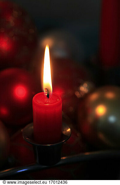 Red burning advent candle and Christmas baubles