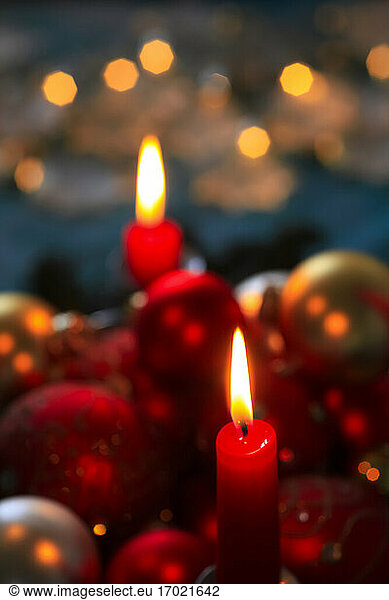 Red burning advent candles and Christmas baubles