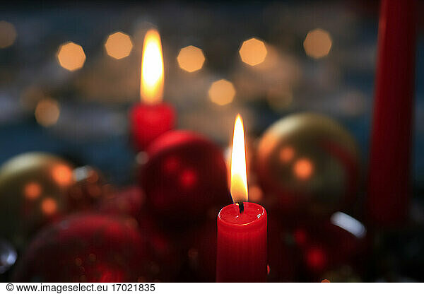 Red burning advent candles and Christmas baubles