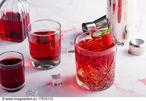 red cocktail with raspberries on a pink background