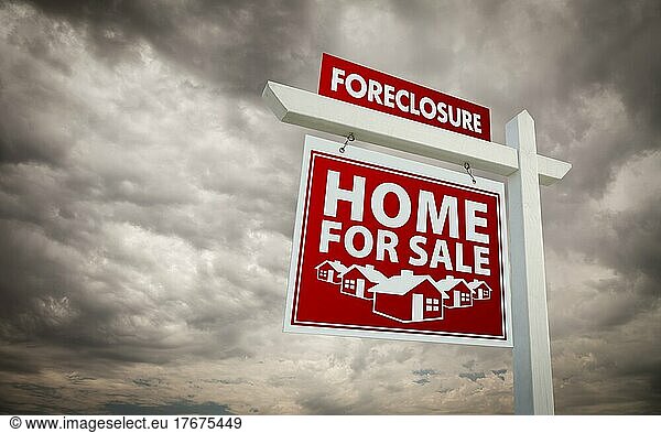 Red foreclosure home for sale real estate sign over ominous cloudy sky