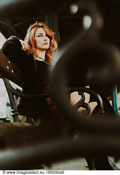 red-haired woman in train station waiting in a bench
