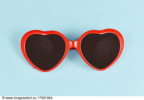 Red heart shaped sunglasses on blue background