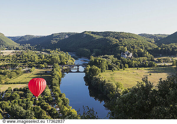 Red hot air balloon flying over Dordogne River