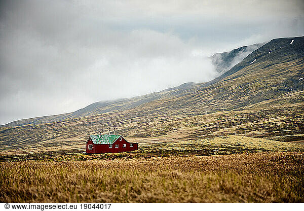 Red house located in mountains with fog