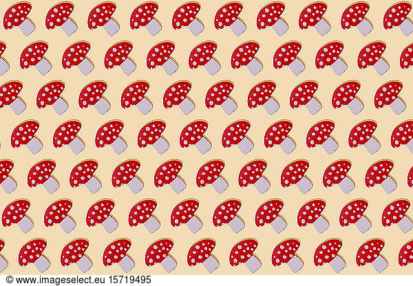 Red mushroom with white spots wooden toy in a row on yellow background
