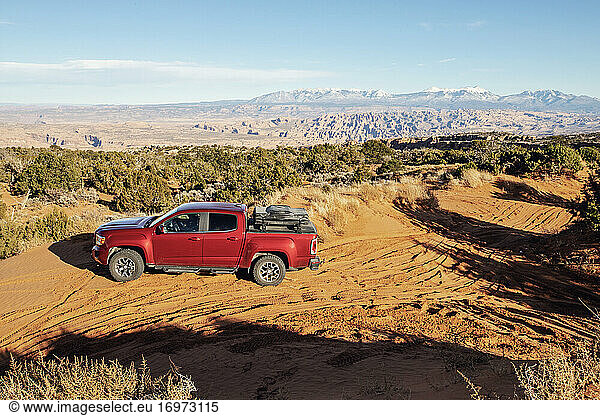 Red overland pickup truck in sand desert near Moab Utah