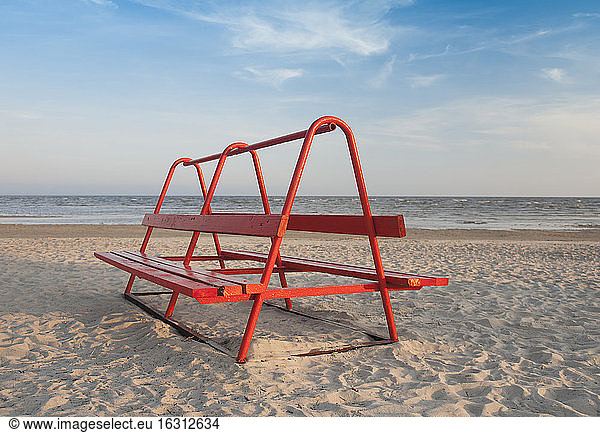 Red Park Bench on the Beach