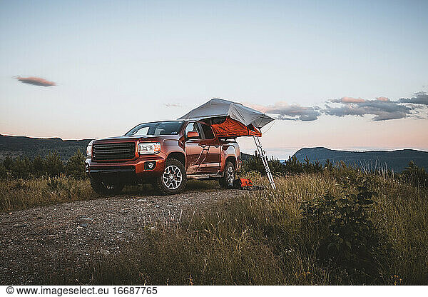 Red pick up truck with roof top tent camping in maine woods with view