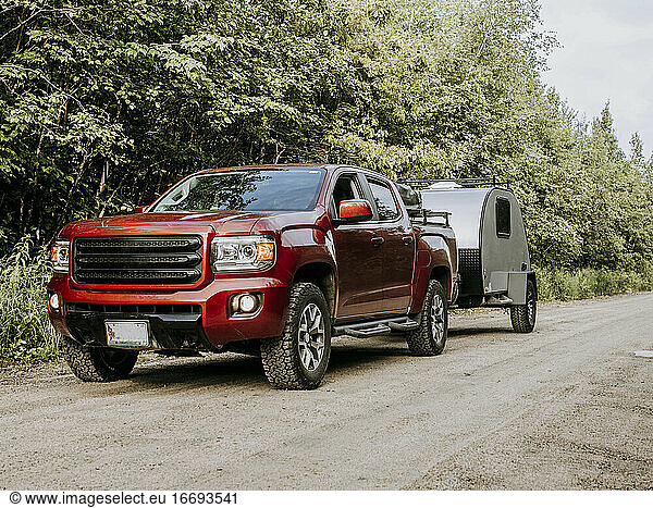Red pickup truck on dirt road hauling teardrop camper trailer RV