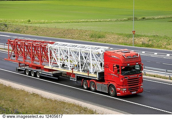 Red Scania semi truck of Ko-Pa Logistics Oy transports part of a crane on flat trailer along motorway in summer in Salo  Finland - June 9  2018.
