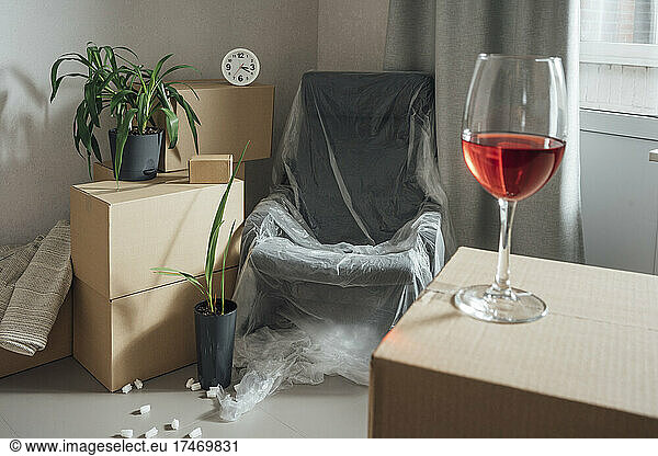 Red wineglass on carton in new apartment