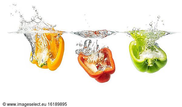 Red  yellow and green peppers fall into the water  studio shot  cutout  Austria  Europe