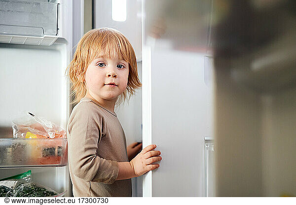 redhead boy looks into the fridge