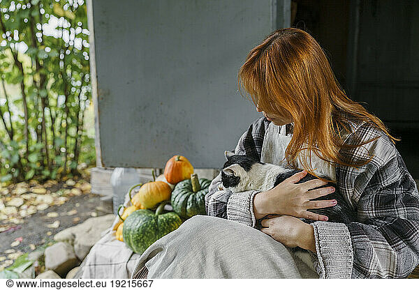 Redhead farmer with cat resting on porch
