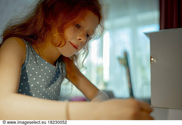 Redhead girl doing homework at home