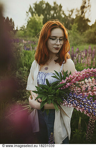 Redhead teenage girl standing with lupin flowers