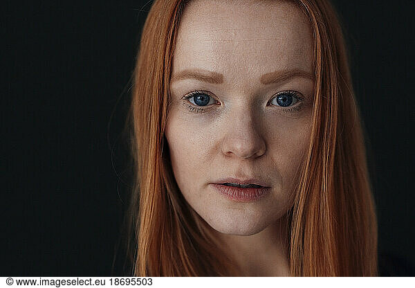 Redhead woman against black background