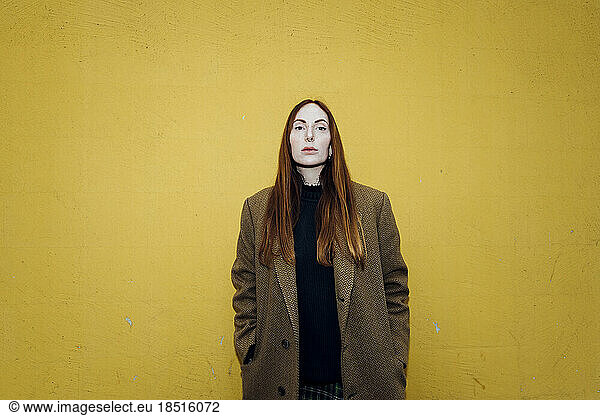 Redhead woman standing in front of yellow wall
