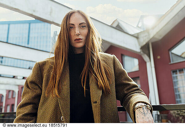 Redhead woman wearing coat standing by railing