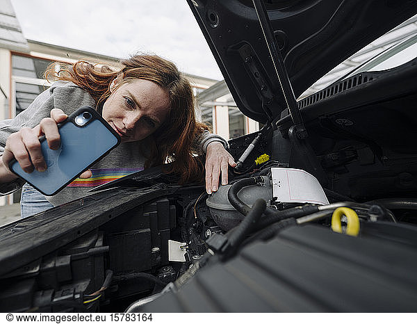 Redheaded woman with cell phone at car