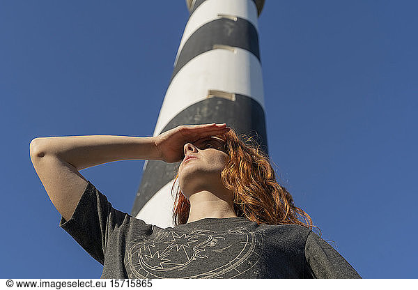 Redheaded young woman at a lighthouse looking out