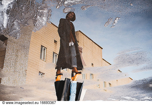 Reflection of a woman posing in front of generic building  full