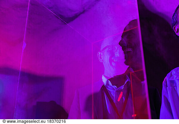 Reflection of cheerful businessman on glass at illuminated convention center