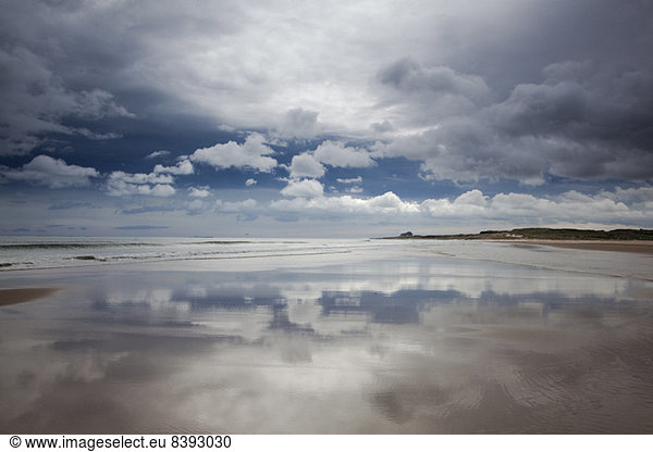 Reflection of clouds on beach at low tide