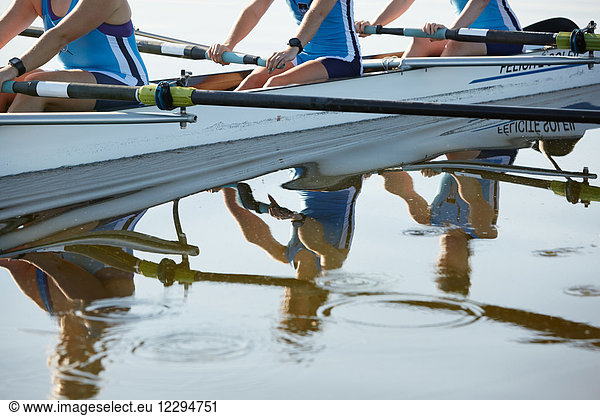 Reflection of female rowers rowing scull on lake