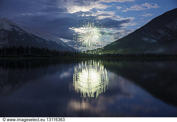 Reflection of fireworks display and mountains in lake