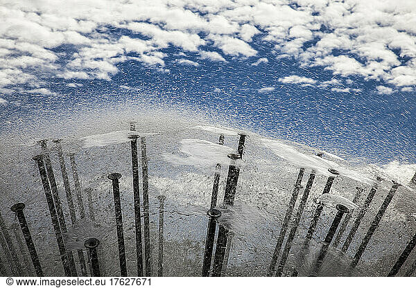 Reflection of sky and clouds in water surface of a modern fountain.