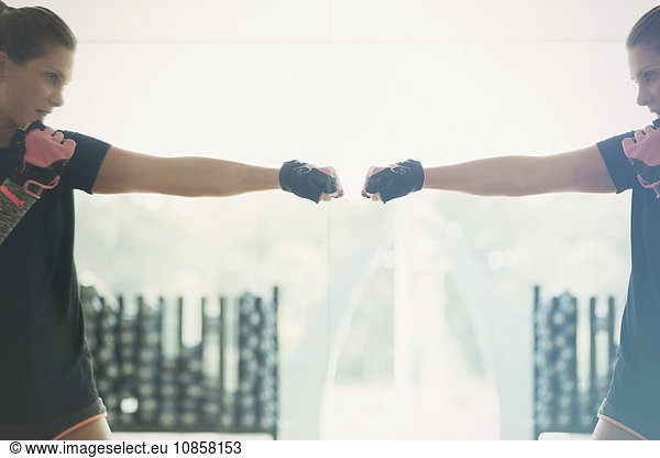 Reflection of woman shadow boxing at gym studio mirror