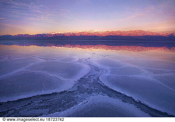 Reflections at sunrise in shallow water on the Badwater playa in Death Valley  California.